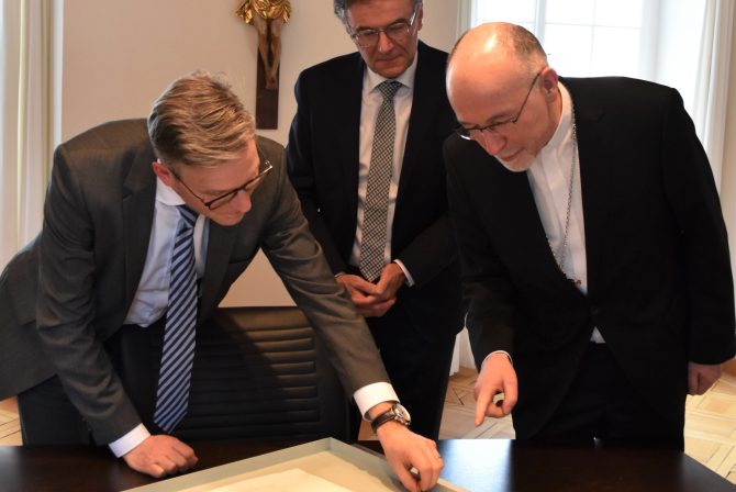 Verwaltungsdirektor Thomas Franck und Administrationsratspräsident Raphael Kühne zeigen dem Nuntius die Gründungsbulle des Bistums.